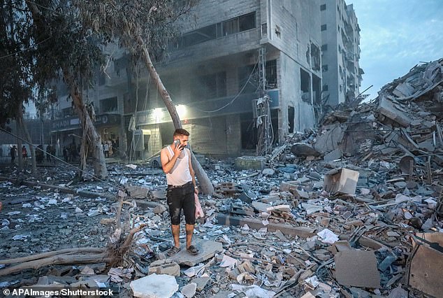 People walk on top of the rubble of a tower destroyed in an Israeli airstrike in Gaza on Saturday