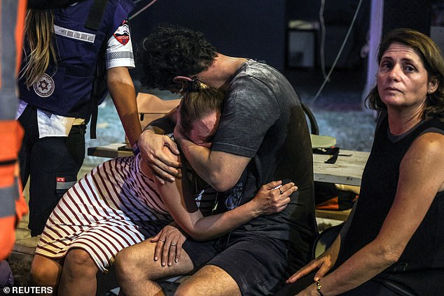 People react at the site where a rocket fired from the Gaza Strip landed in Tel Aviv, Israel