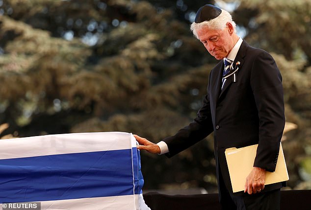 Former US President Bill Clinton touches the flag-draped casket of former Israeli President Shimon Peres after eulogizing him during his burial ceremony at Mount Herzl Cemetery in Jerusalem, Israel in 2016