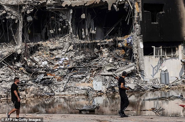 Israelis walk past a blown-up police station in Sderot that was destroyed during a battle with Hamas militants who overtook the building