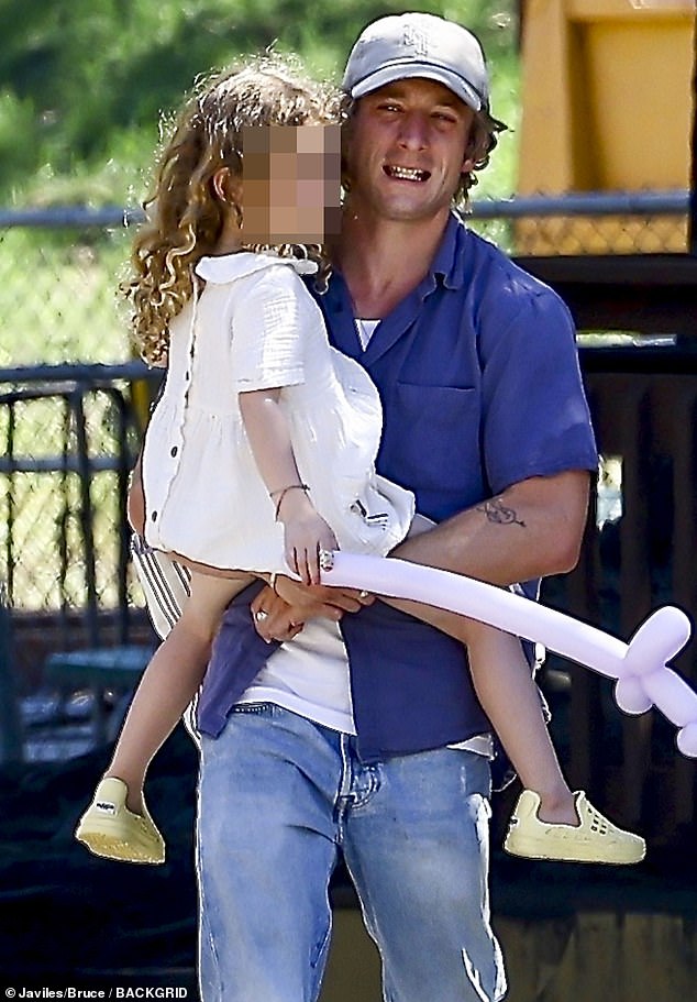 Doting dad: The Shameless star kept a tight grip on one of his daughters as she held a purple balloon animal on Sunday