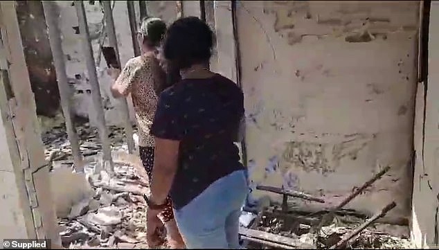 Women walk through the ruined remains of houses in Kibbutz Re'im, a settlement of 500 families near Gaza