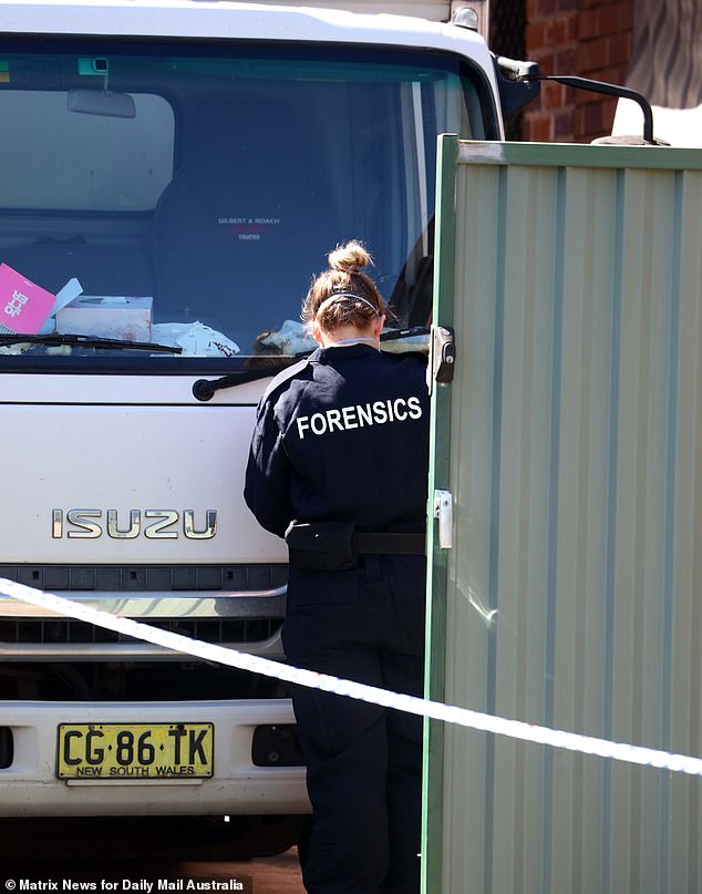 A coroner's officer sweeps Mr Li's truck from the road where he was found dead at the weekend