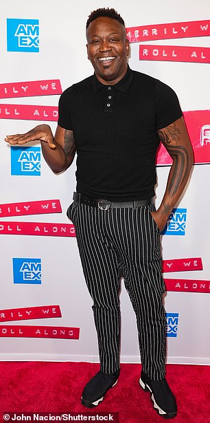 Take it easy: Titus Burgess kept it relatively casual in a black polo shirt which was tucked into a pair of skinny striped trousers