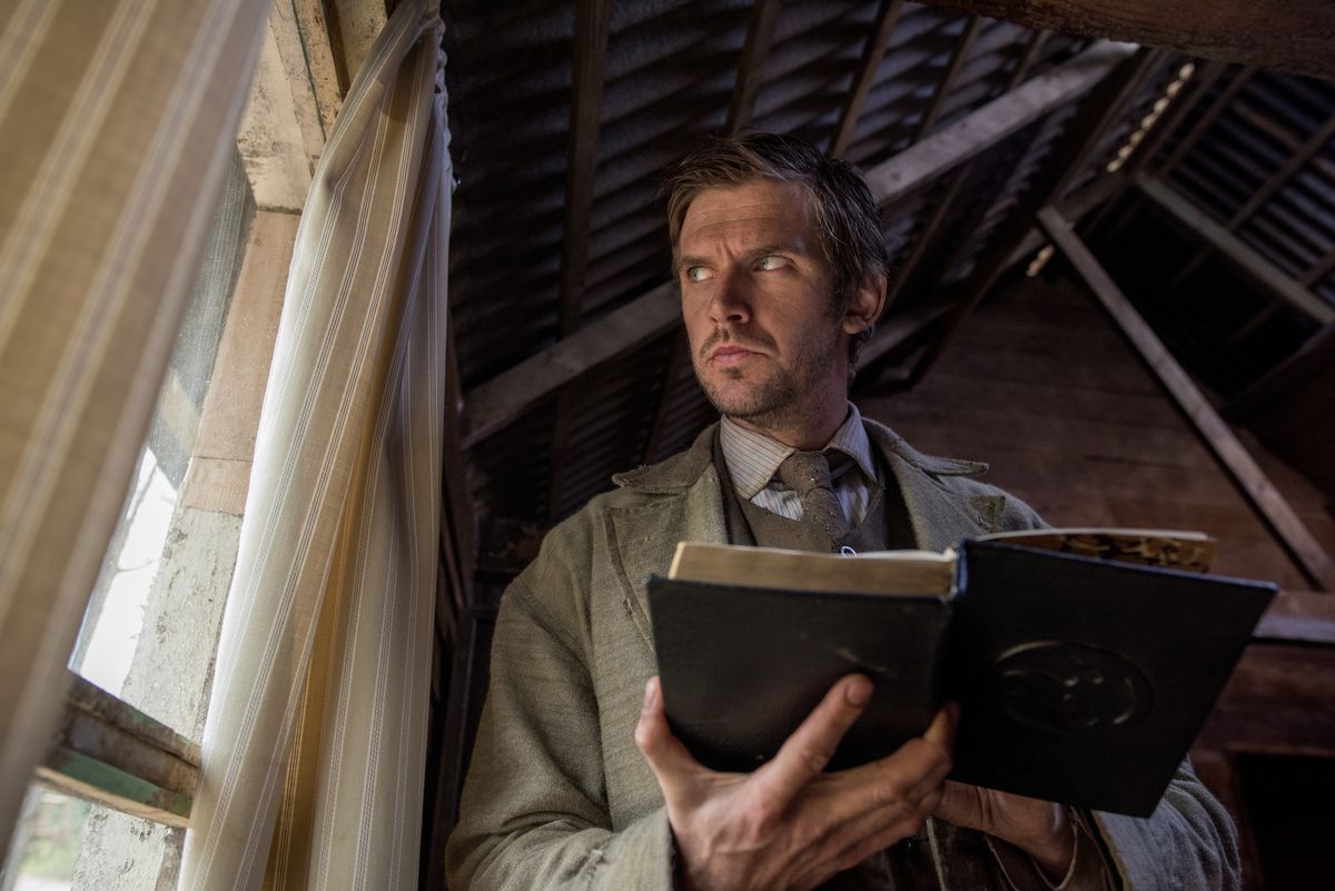 Dan Stevens as Thomas Richardson in Apostle looks suspiciously out the window while reading the Bible