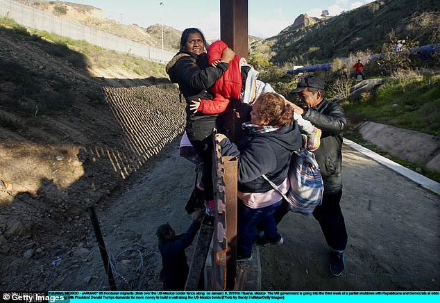 Migrants scale the wall near San Diego, trying to make sure a child doesn't fall.