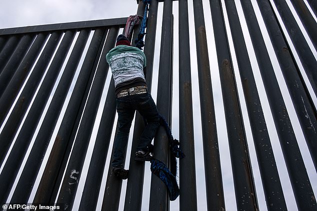 A migrant slides down the American side of the wall.