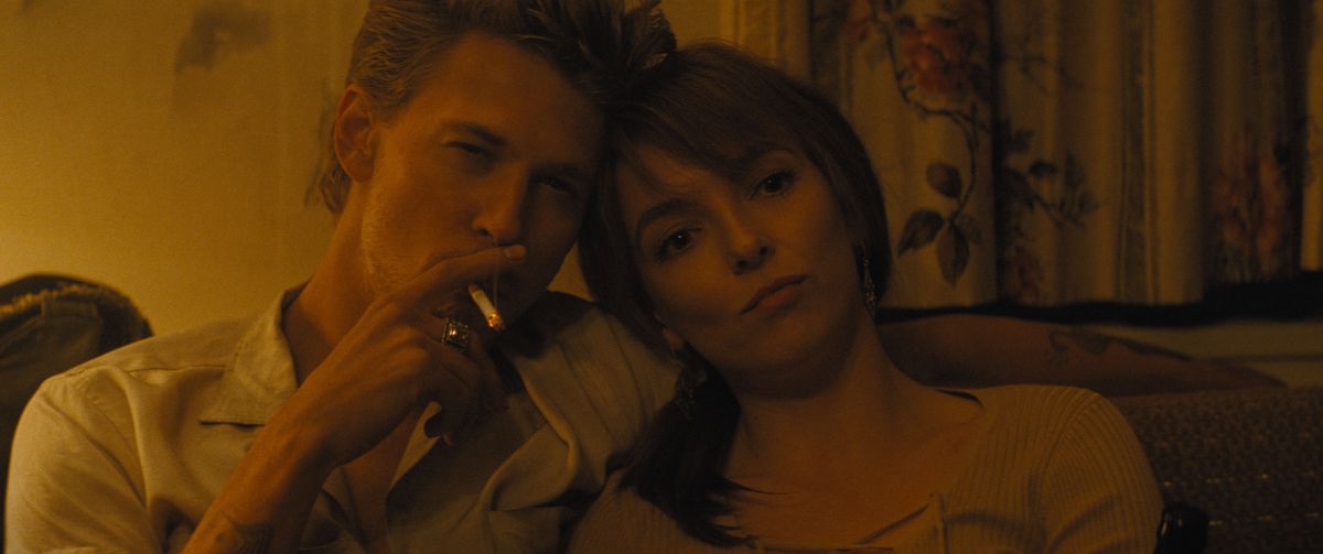 Austin Butler smokes and looks cool while leaning his head on Jodie Comer's head in The Bikeriders