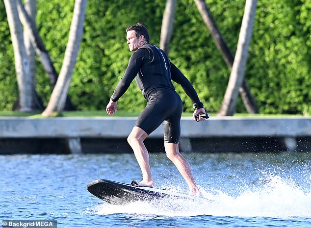 The motorized surfboard comes with a remote control that can be seen in Brady's left hand