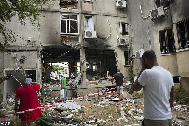 Israelis inspect a damaged residential building after it was hit by a rocket from the Gaza Strip in Ashkelon, Israel, Monday, Oct. 9, 2023.