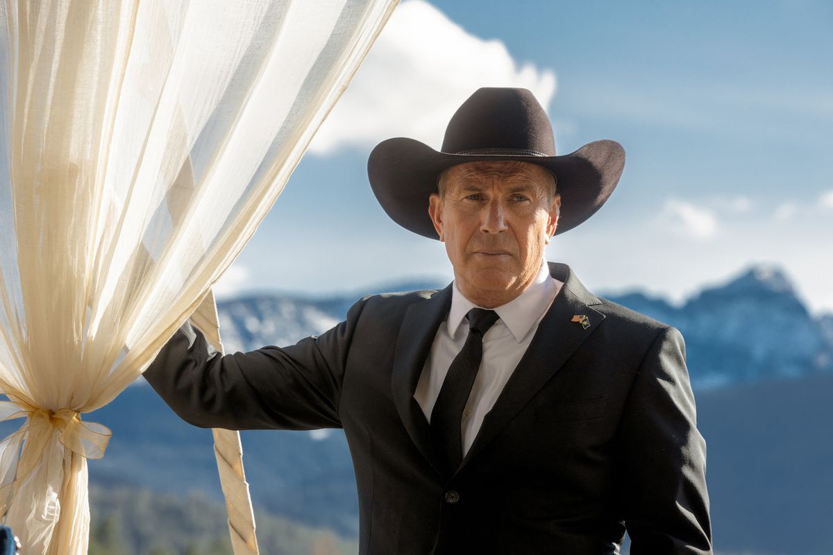 Kevin Costner wearing a black suit and a black cowboy hat facing the camera in Yellowstone