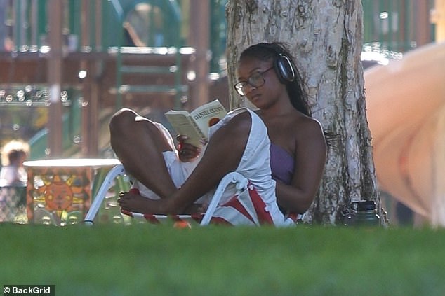 Wearing a pair of $550 Airpods Max headphones to block out distractions, the 22-year-old seems oblivious to her surroundings as she enjoys her book