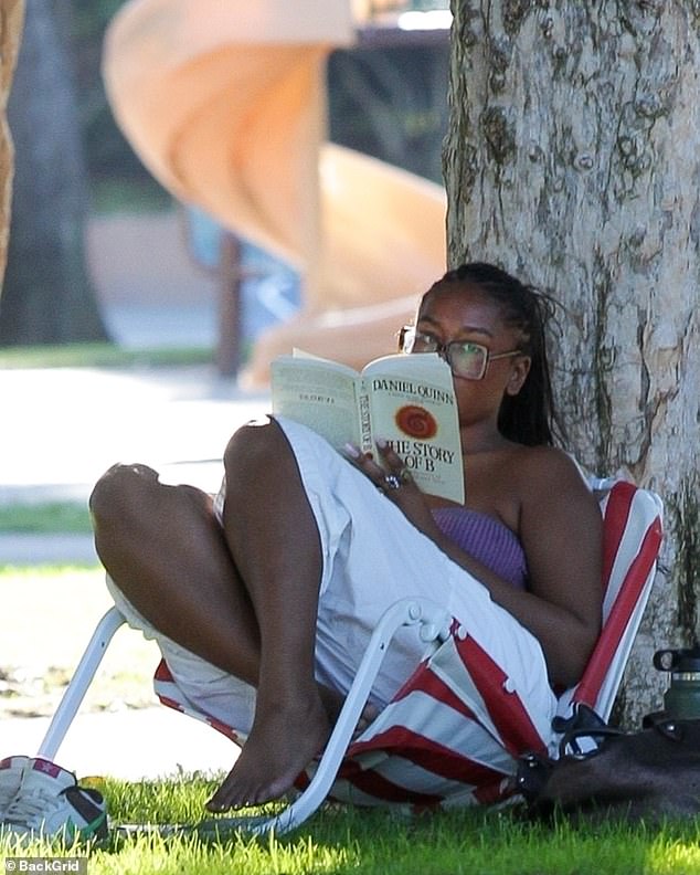 Her sneakers are off as she kicks back in her low folding chair under the shelter of a tree