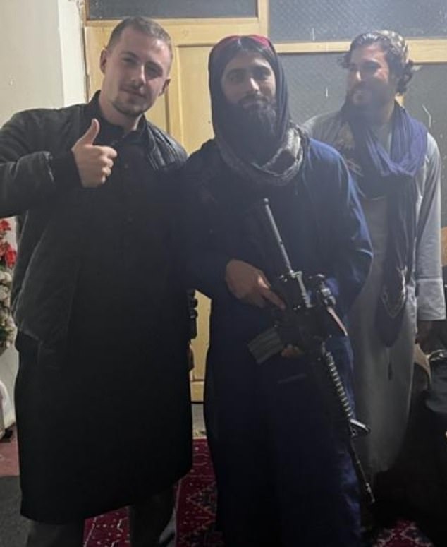 Miles Rutledge (left) raises his hands as he stands next to a member of the Taliban holding an assault rifle