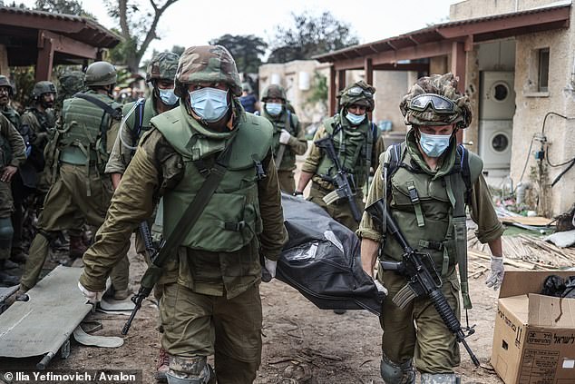 Israeli forces remove the dead bodies of Israeli residents from a destroyed house as fighting between Israeli troops and Hamas Islamist militants continues, October 10, 2023