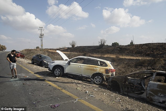 A man walks past destroyed cars that were attacked by Palestinian militants on October 10, 2023 in Kfar Aza, Israel