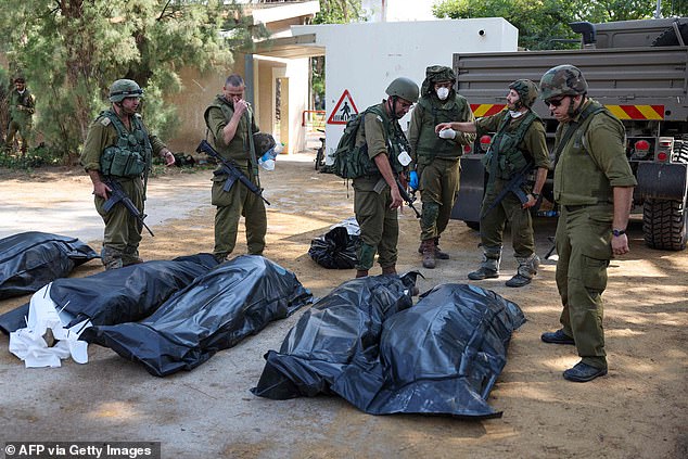 Israeli soldiers prepare to remove the bodies of their compatriots killed during an attack by Hamas in Kfar Aza