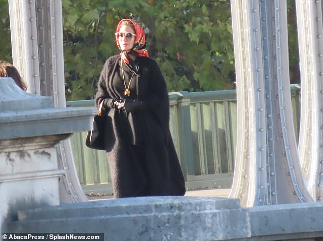 Hiding in plain sight: A third wardrobe change showed Angelina in a long black winter coat and a bright red scarf wrapped around her head, accented by large sunglasses and a dangling necklace