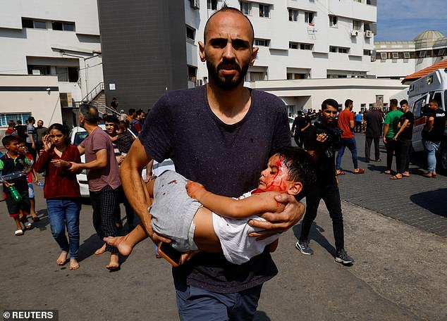 A man carries a child injured by Israeli airstrikes to a hospital in Gaza City on October 11