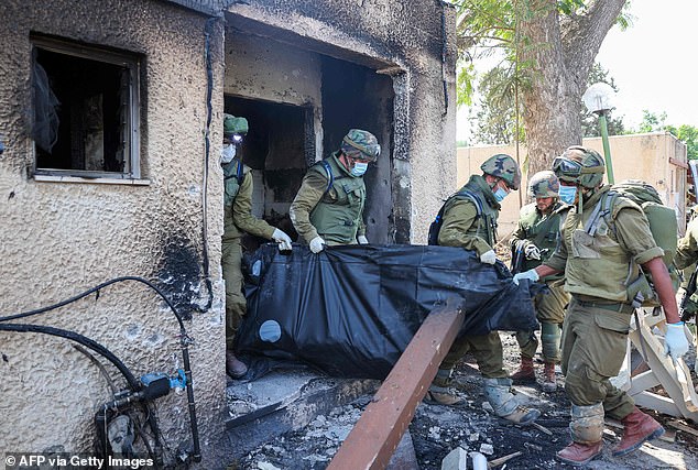 Troops remove the bodies of victims killed during an attack by Hamas terrorists in Kfar Aza on Tuesday