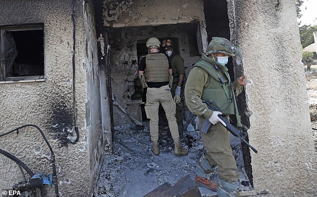 Israeli soldiers search for the bodies of Israelis killed in Kfar Aza Kibbutz near the border with Gaza on Tuesday