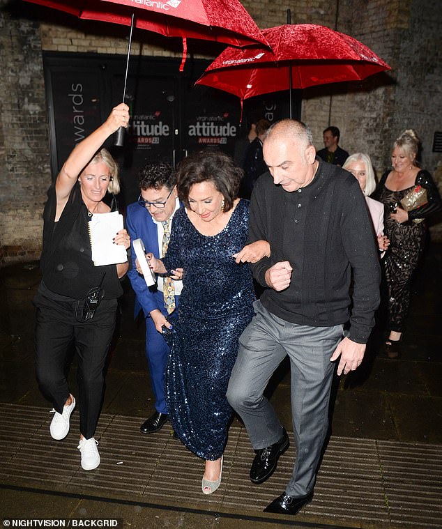 Diva!  Shirley Bassey had some guards protecting her from the rain as she got into her car later