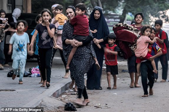 Fleeing women walk with children along a street in Gaza City on October 11, 2023. At least 30 people have been killed and hundreds injured as Israel pounded the Gaza Strip with hundreds of airstrikes overnight, a Hamas government official said on 11 October.  The Israeli military confirmed that it struck several Hamas targets overnight in the Palestinian enclave.  (Photo by MOHAMMED ABED/AFP) (Photo by MOHAMMED ABED/AFP via Getty Images)