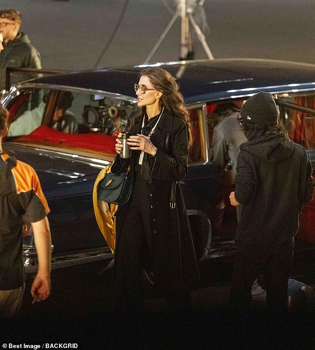 Keeping warm: Angelina held a bottle in her hand as filming went into the night