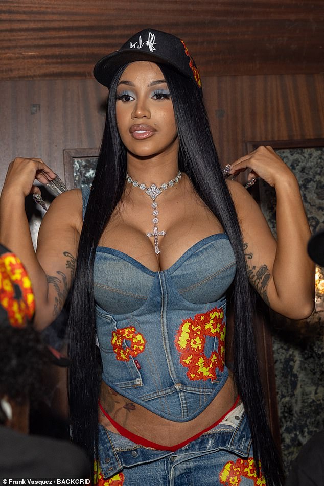 Looking good: Cardi opted for long black hair for the event which she straightened straight and accessorised with a black Set It Off baseball cap