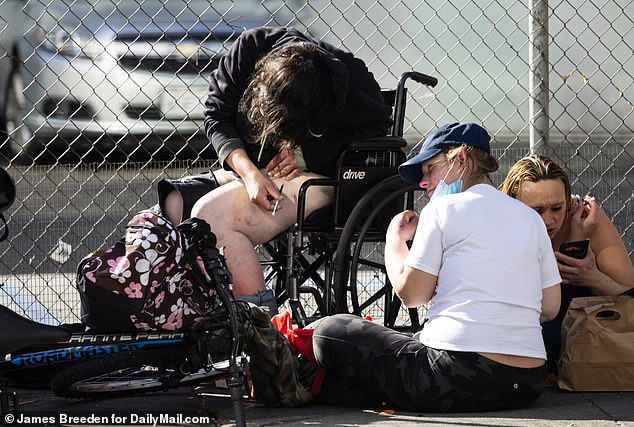 A woman in a wheelchair injects drugs at San Francisco's notorious open-air drug market