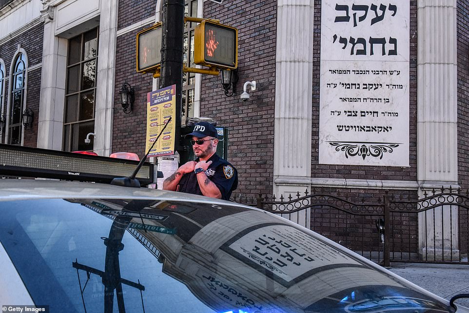 A member of the New York Police Department patrols in front of the Congregation Bais Yaakov Nechamia Dsatmar synagogue in the Williamsburg, Brooklyn