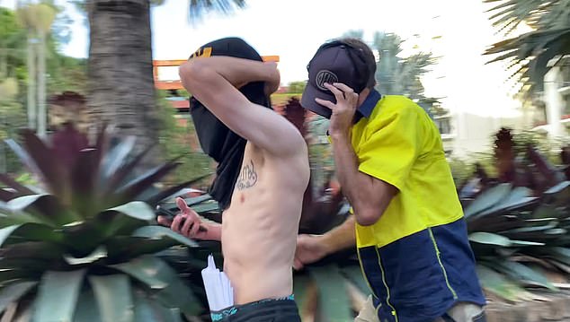 One man covered his face with a T-shirt, while another, wearing a hi-vis shirt, covered his face with a cap