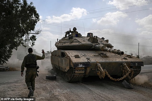 An Israeli soldier maneuvers a Merkava main battle tank as it deploys along with other tanks along the border with the Gaza Strip in southern Israel on October 13, 2023