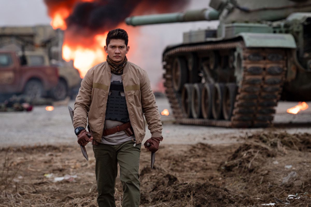 Iko Uwais walks away from the explosion in Expend4bles, holding a spiked weapon.