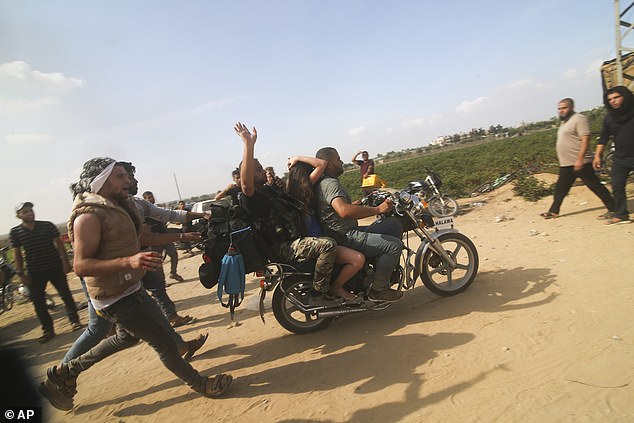 Palestinians transport a captured Israeli citizen, center, from Kfar Aza Kibbutz to the Gaza Strip on Saturday