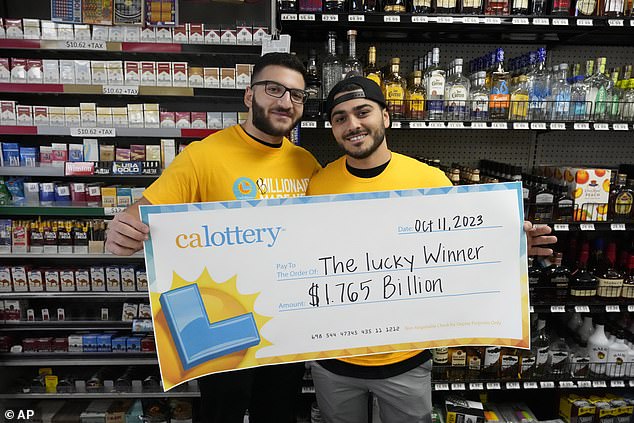 Jonathan Khalil, left, and Chris Khalil, sons of the store's co-owners, hold up a ceremonial check presented to them by lottery officials