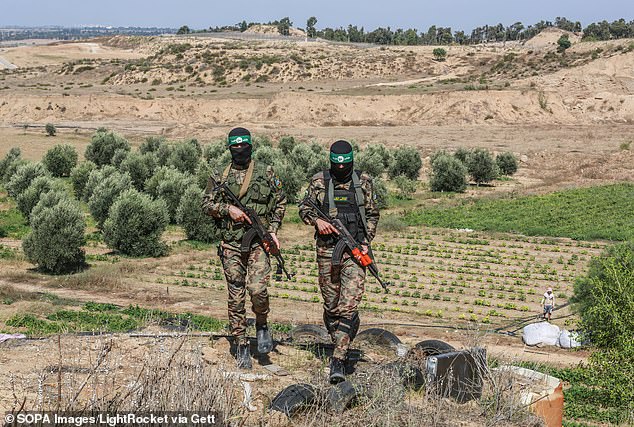 Palestinian fighters from the armed wing of Hamas take part in a military parade in front of an Israeli military site