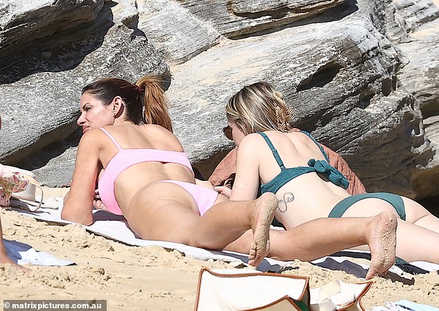 After taking a dip in the water, Alessandra spent time sunbathing next to her friend on a beach towel