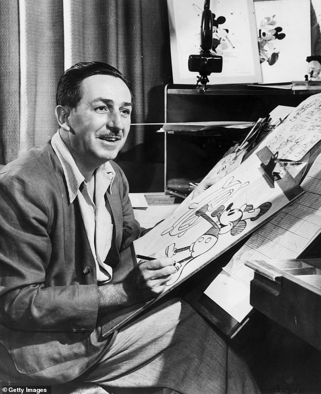 Walt Disney (1901 - 1966) sits at his drawing table in his studio and draws a sketch of his character Mickey Mouse