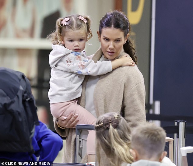 Dressed casually: Rebecca cut a casual figure in a pale gray tracksuit and beige woolen coat and had her hands full as she carried her three-year-old daughter