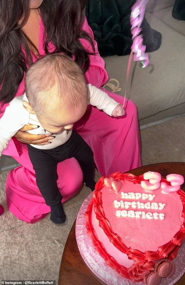 Let me go!: Scarlett holds baby Jude, who does a great job of trying to blow out the candles on her mom's heart-shaped cake with pink and red frosting