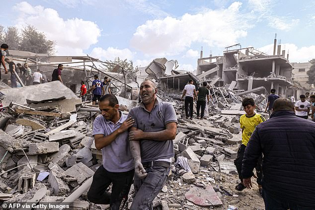 A Palestinian reacts as he is helped over the rubble after an Israeli airstrike on buildings in Rafah, southern Gaza Strip on October 17, 2023