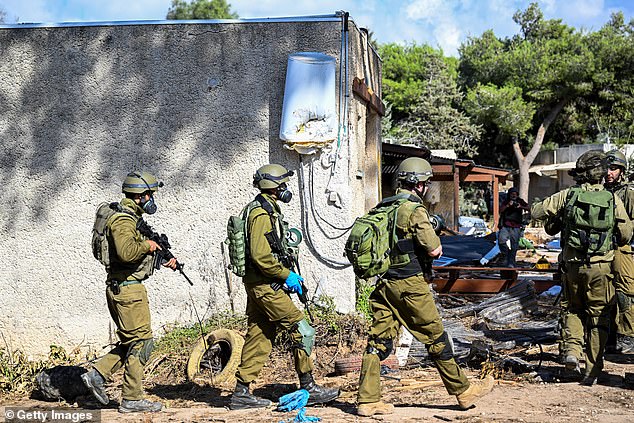 IDF soldiers move through neighborhoods destroyed by Hamas militants after attacking this kibbutz days earlier near the Gaza border on October 15, 2023 in Kfar Aza, Israel