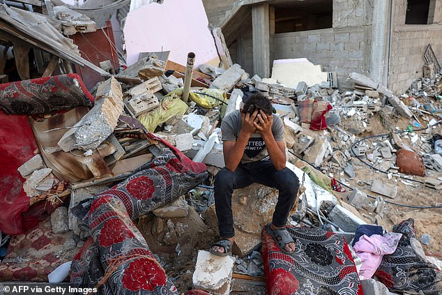 A Palestinian youth reacts as he sits on the rubble of a destroyed house after an Israeli military attack on the Rafah refugee camp, southern Gaza Strip on October 15, 2023