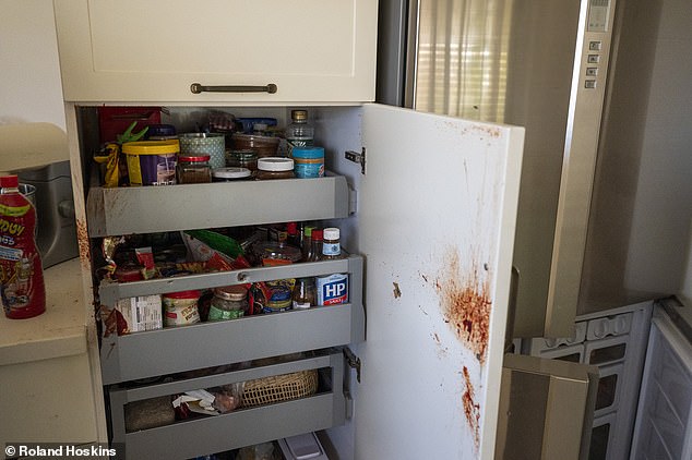 A blood-spattered kitchen cabinet door stands open, with HP sauce prominently displayed on the front rack