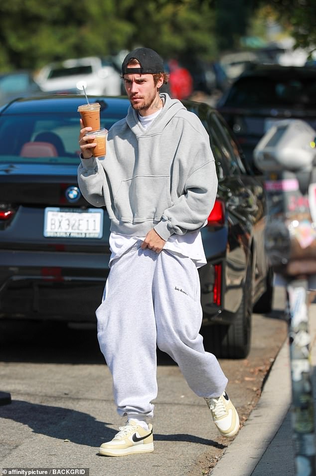 Heavy pockets: After downing the caffeinated beverages, he was seen walking to his car with two in one hand while the other was busy pulling up a tracksuit