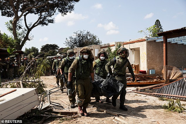 Israeli soldiers carry the body of a victim of a deadly Hamas attack last week on Kibbutz Kfar Aza in southern Israel