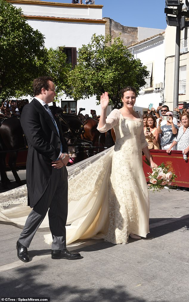 The bride stunned in a lace and embroidered dress with a long train, with her hair braided in a boho-inspired updo