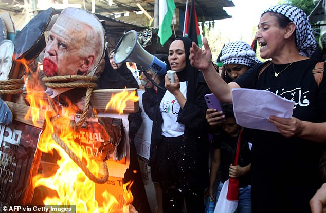 A woman speaks as an image of US President Joe Biden is burned during a protest in the Palestinian refugee camp Ain al-Hilweh near the southern Lebanese port city of Sidon on October 18, 2023