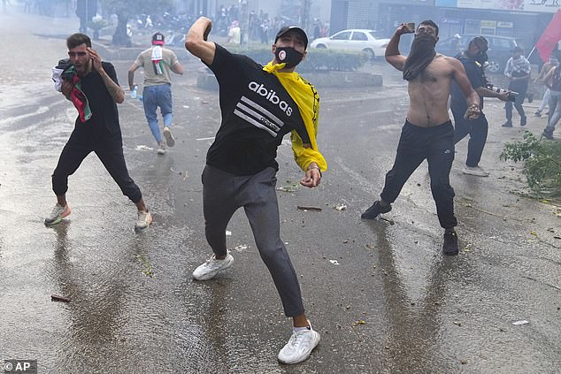 Protesters throw stones at riot police during a demonstration in solidarity with the Palestinian people in Gaza, near the US embassy in Aukar, a northern suburb of Beirut